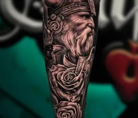 Black and grey bearded warrior portrait tattoo with roses on a lower leg