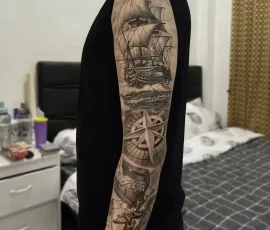 Healed black and grey pirate ship and compass sleeve tattoo