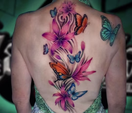 Floral tattoo in watercolor style with pink lilies and butterflies, on back