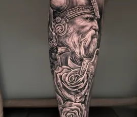 Healed black and grey bearded warrior portrait tattoo with roses on a lower leg