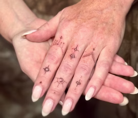 Contemporary tattoo of tiny stars and sparkles across the fingers