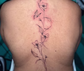 Contemporary tattoo of a fine line vine with small flowers running down the spine, on back