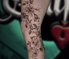 Floral tattoo of trailing flowers and leaves, on leg