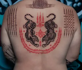 Sak Yant tattoo with twin tigers in red and black, on upper back