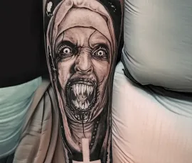 Healed black and grey horror nun portrait tattoo on a forearm