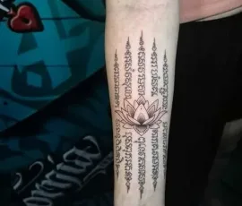 Sak Yant tattoo with a lotus and sacred script column